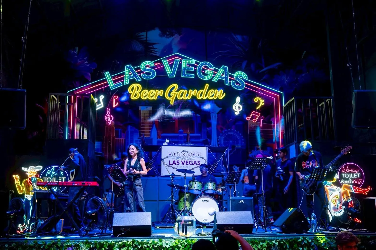 The singer and band on stage under the Las Vegas Beer Garden neon, seen from the KQ Bar tables